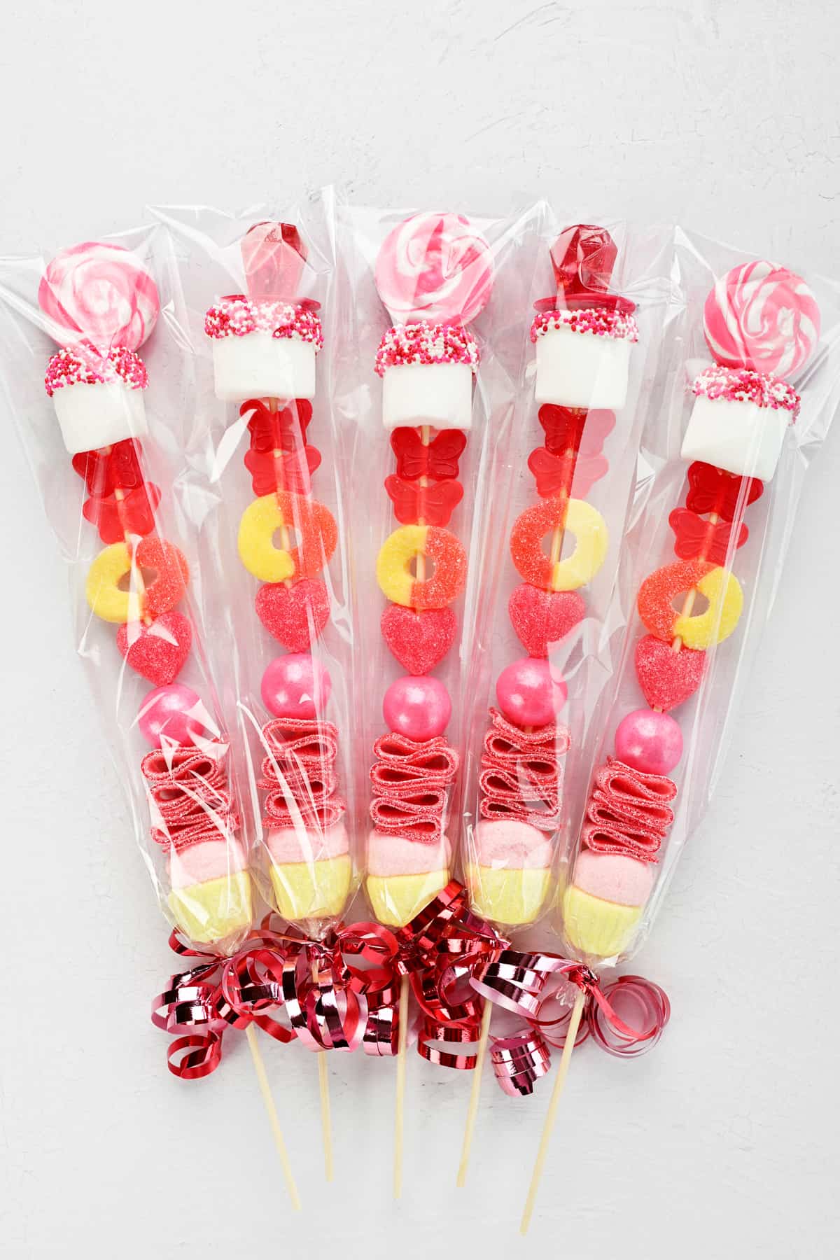candy sticks packaged in cellophane with pink ribbons.