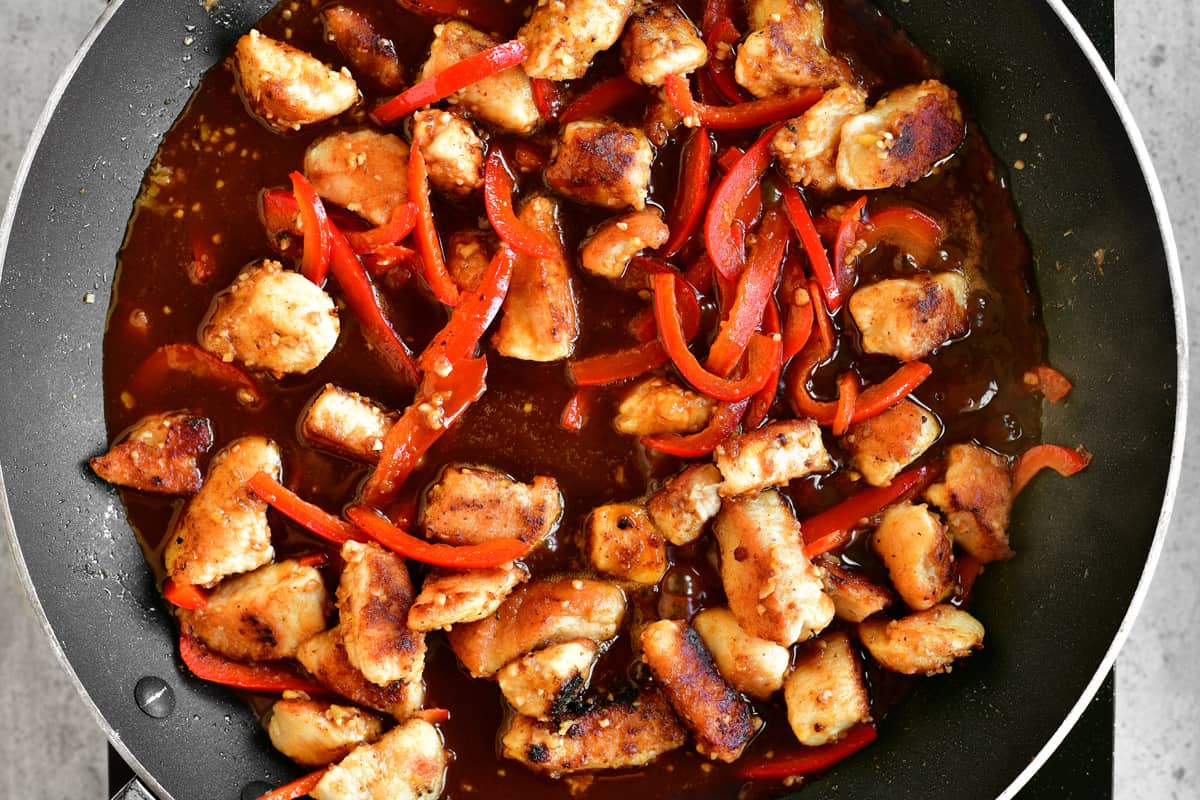 chicken, peppers and sauce cooking in a pan.