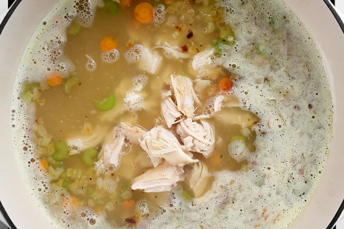 chicken, celery, carrots and onion cooking in a pot.