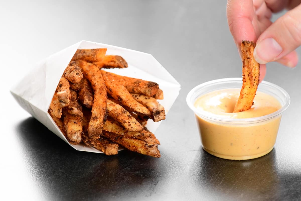 nacho fries in a paper cup and cheese sauce.
