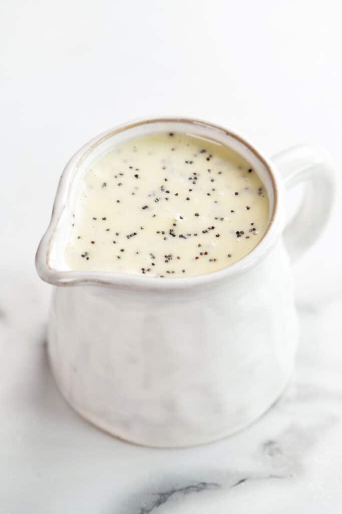 a white pitcher holding poppy seed dressing.