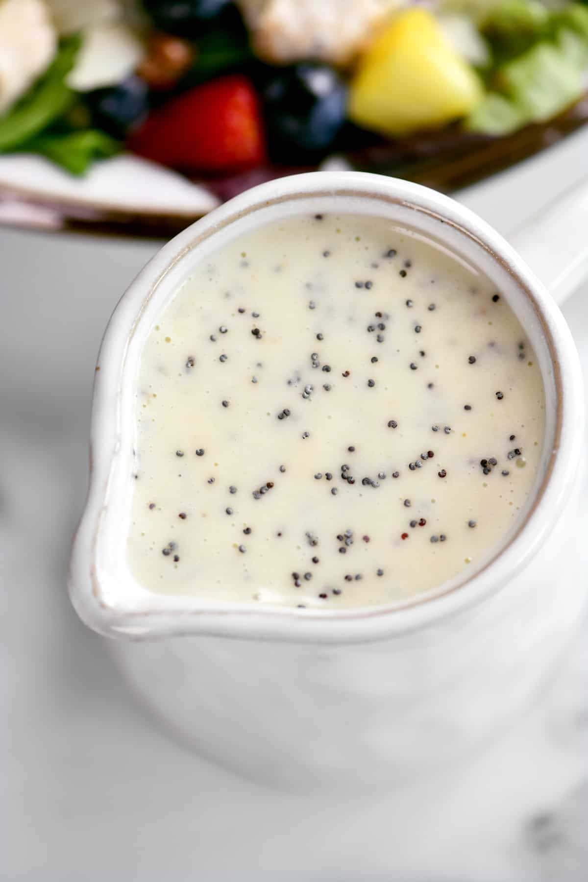 top down view of poppy seed dressing in a white pitcher.
