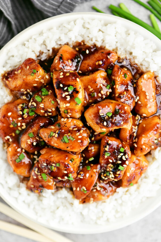 sesame chicken in a white bowl with rice.