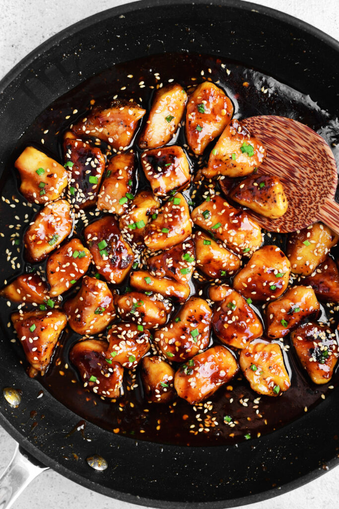 sesame chicken in a skillet with sauce.