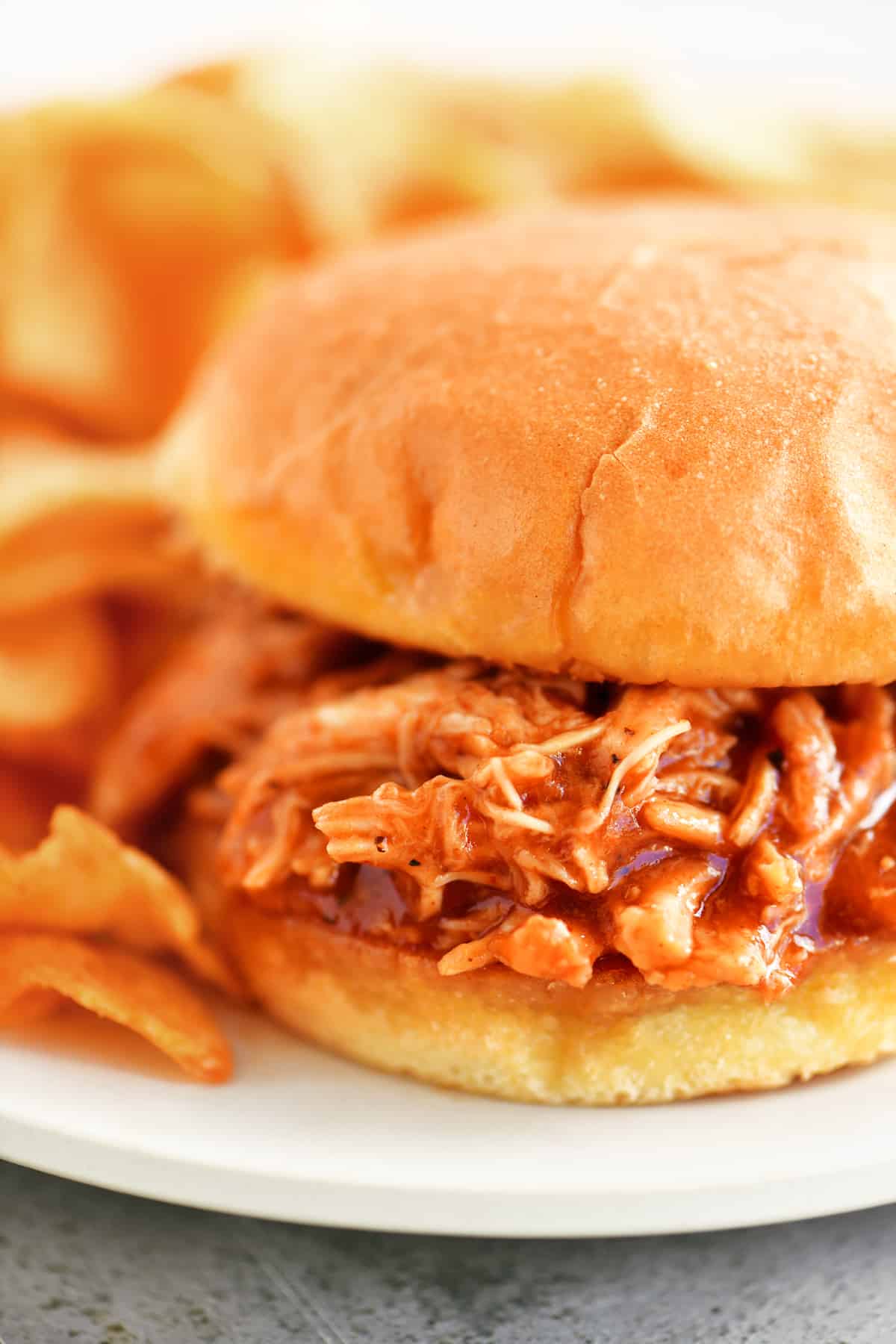 barbecue chicken sandwich on a plate with chips.