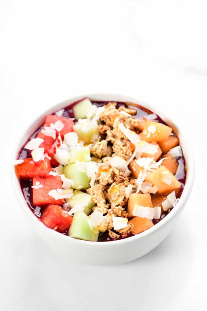 a bowl full of fruit and coconut and granola.