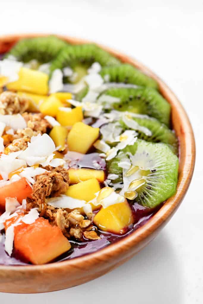 kiwi, pineapple, granola and coconut in a wooden bowl.