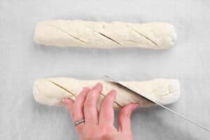 hands using a knife to slice the bread dough.