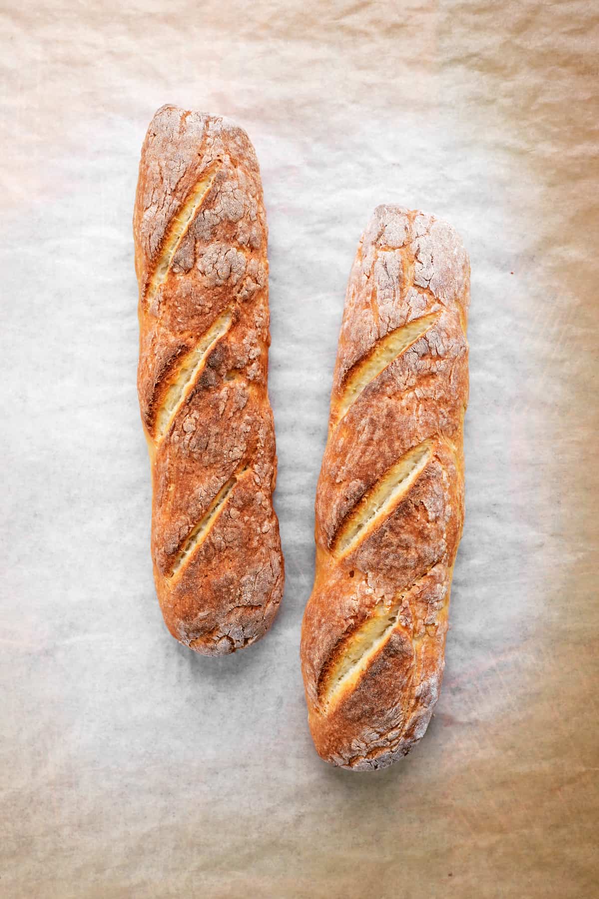 two loaves of bread on a piece of parchment paper.