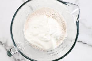 yogurt and flour in a glass mixing bowl.