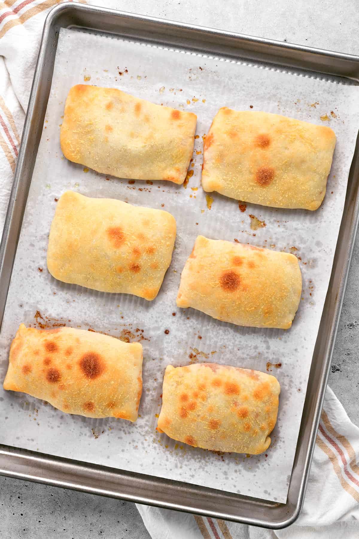 baked pizza pockets cooling on a baking sheet.