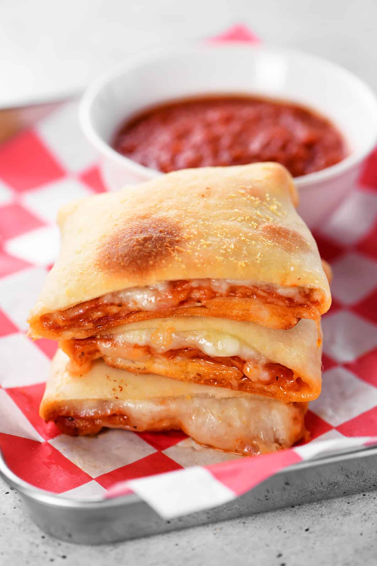 two-ingredient dough pizza pockets and a small bowl of pizza sauce on a metal serving tray.