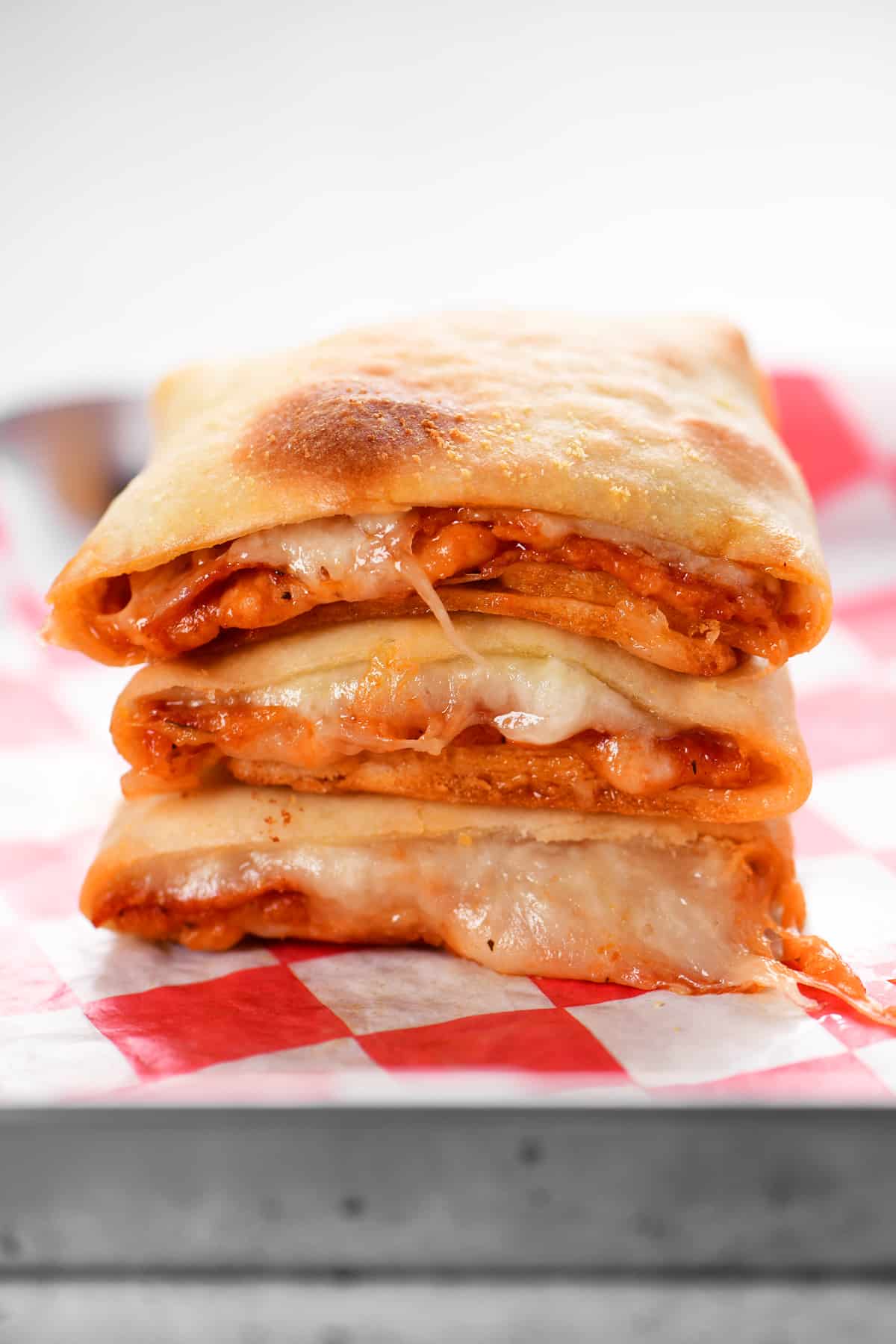 cheese oozes out of sliced pizza pockets that are stacked three high.