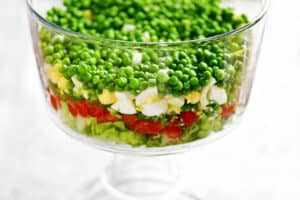 peas, eggs. onions, tomatoes and lettuce in a dish.