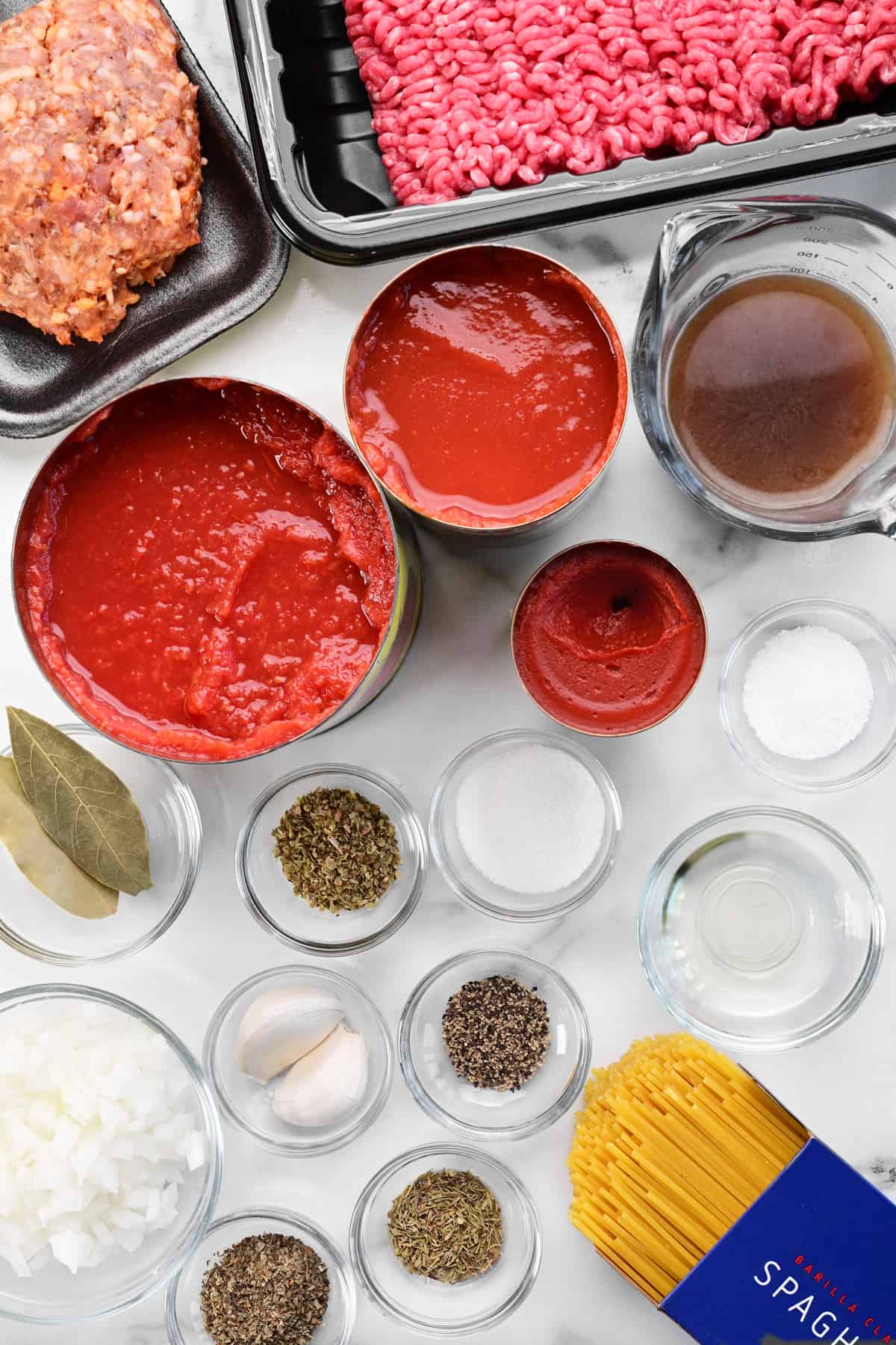 meat, sauces, and spices in bowls on a marble countertop.