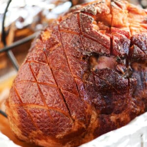 a honey glazed ham in a roasting pan.