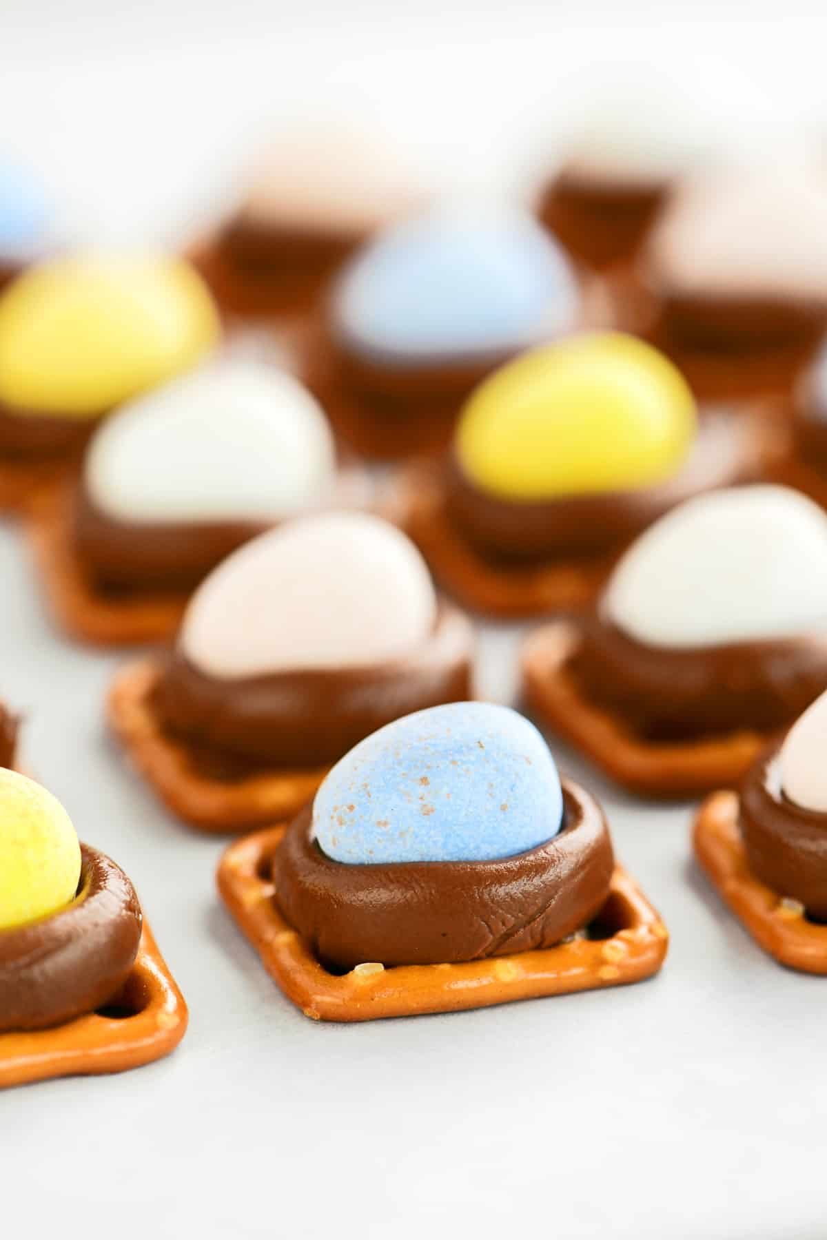 side view of pretzels with Hersheys Kisses and mini eggs on top.