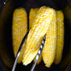 Removing corn on the cob from a crock pot.