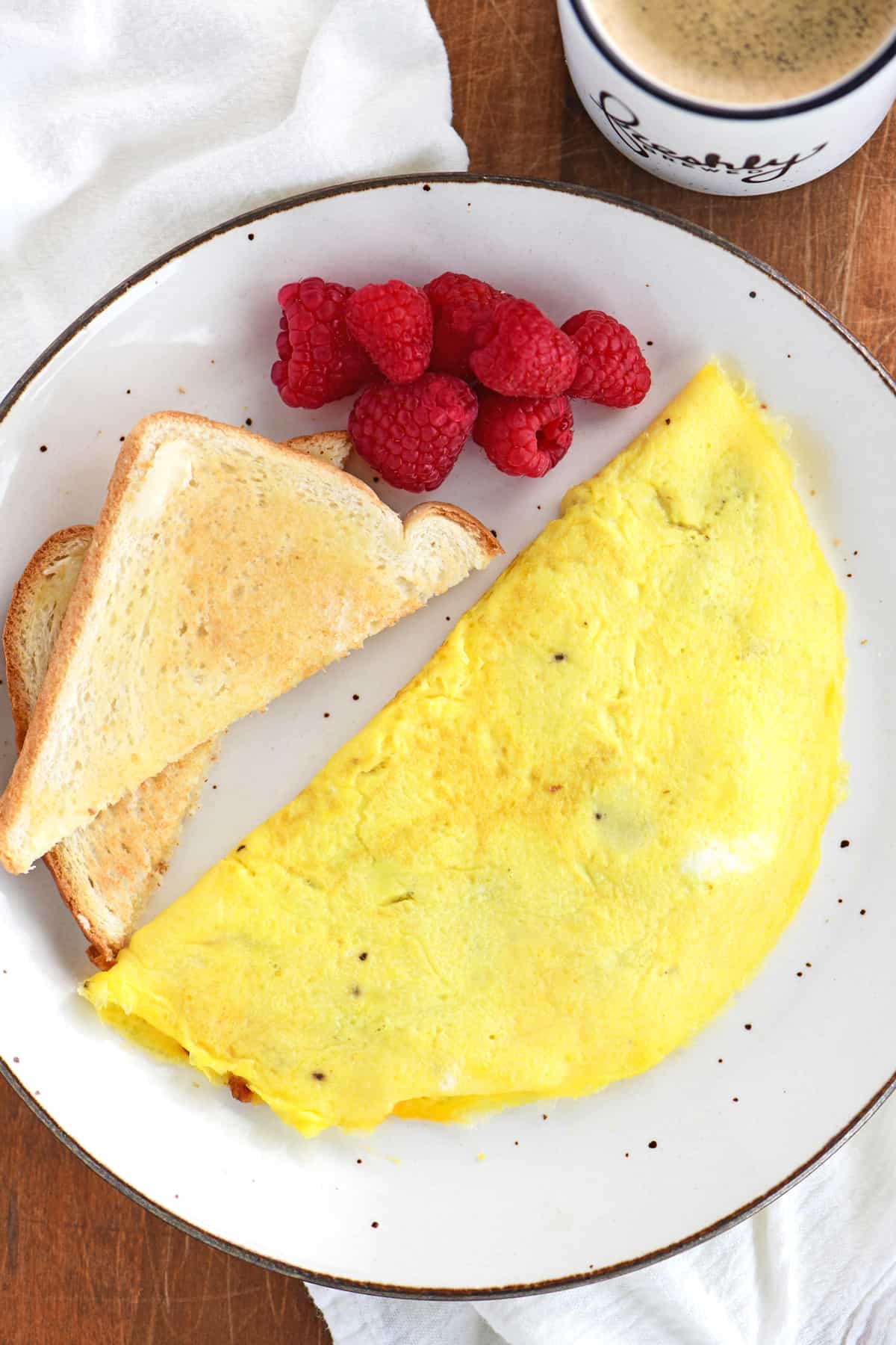 a plate with toast, an omelet, and berries on it.