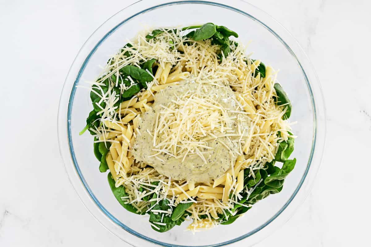 Spinach pasta salad ingredients in a glass bowl.