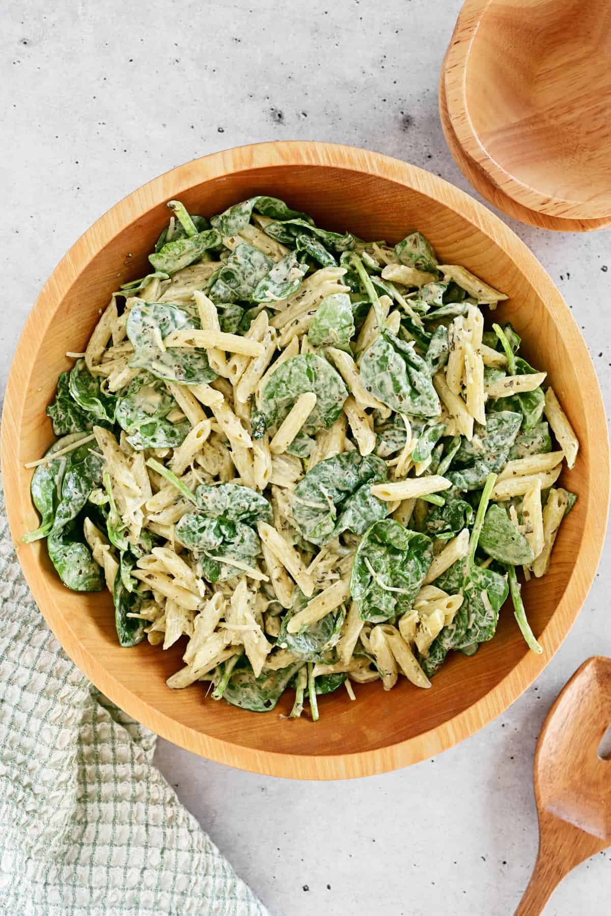 Spinach pasta salad in a wooden bowl.