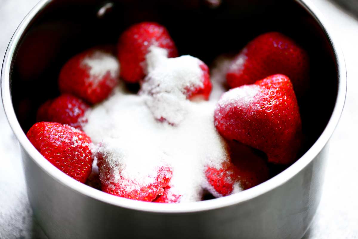 Strawberries and sugar in a saucepan.