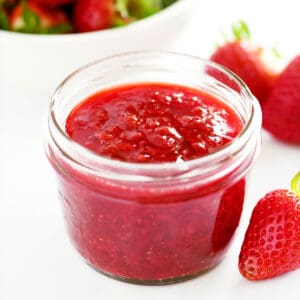 A jar holding strawberry sauce.