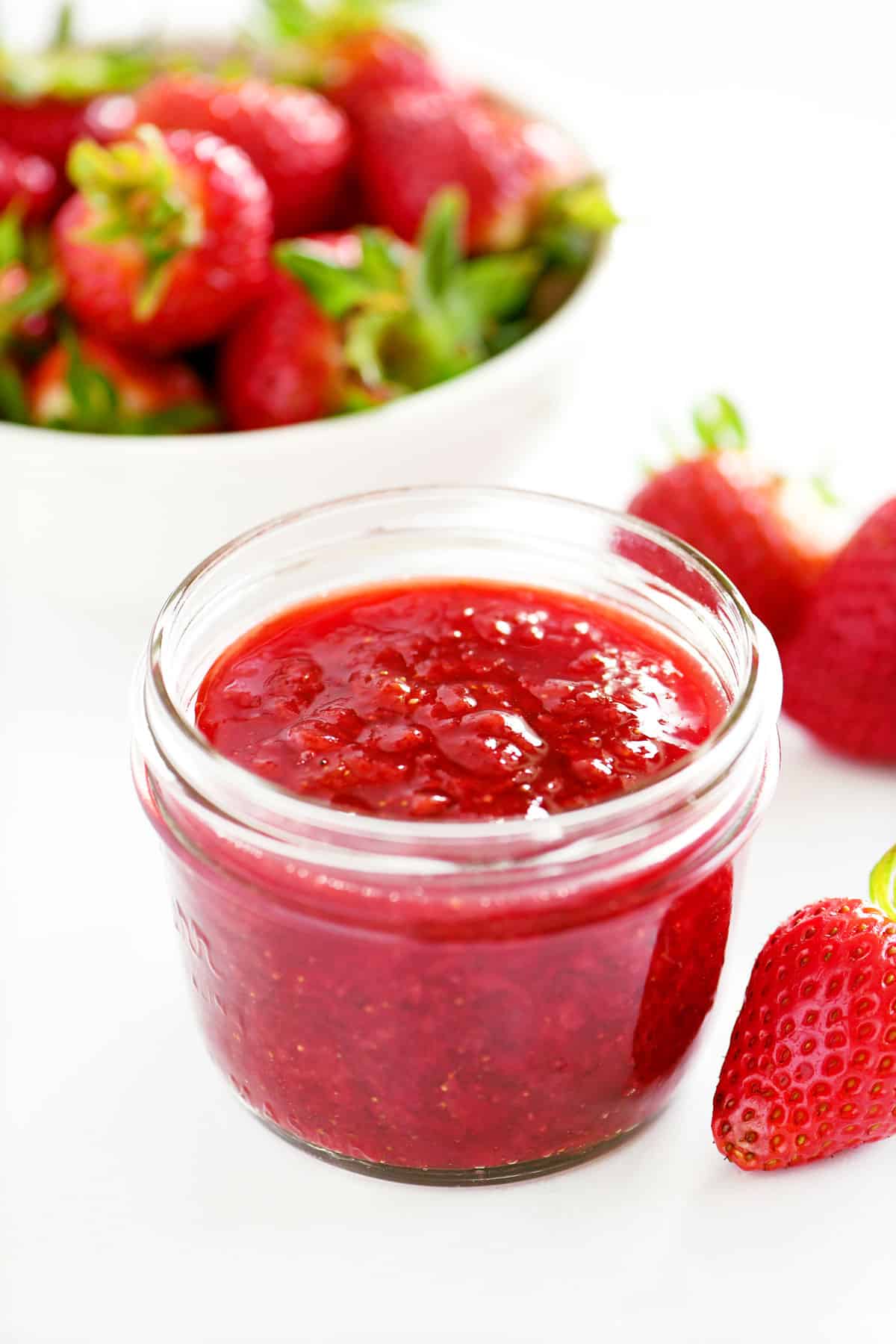 A jar with strawberry sauce inside.