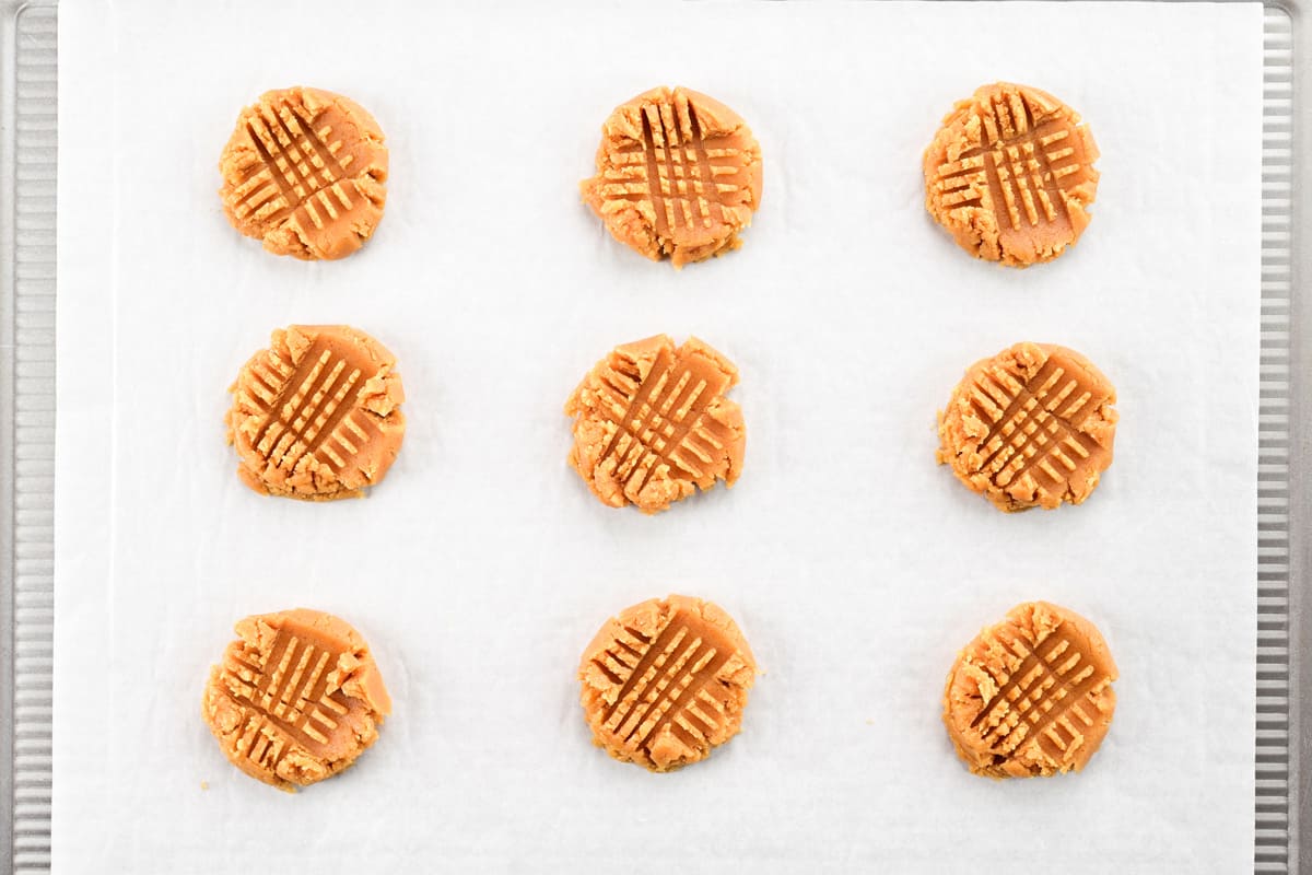 Peanut butter cookie dough with fork marks pressed into the tops.