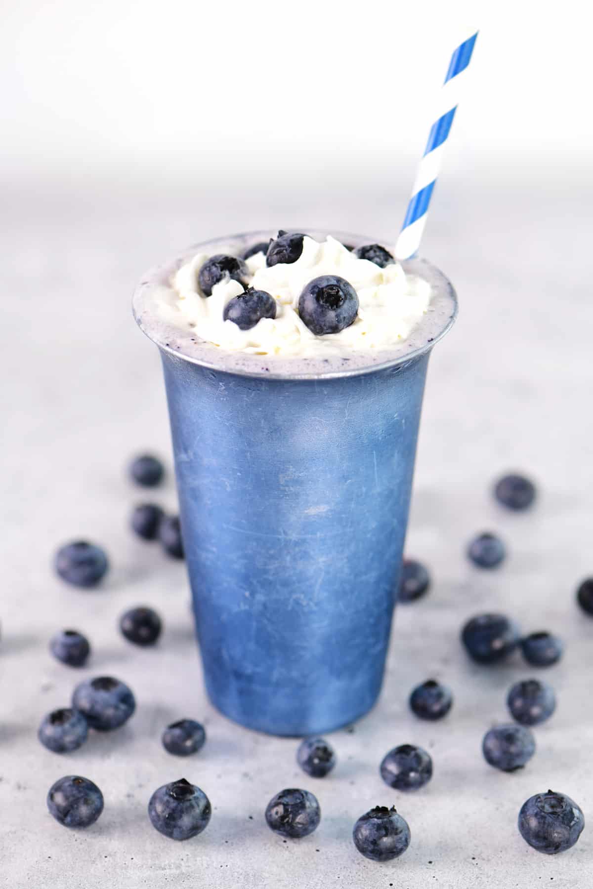 A blueberry milkshake in a blue cup.