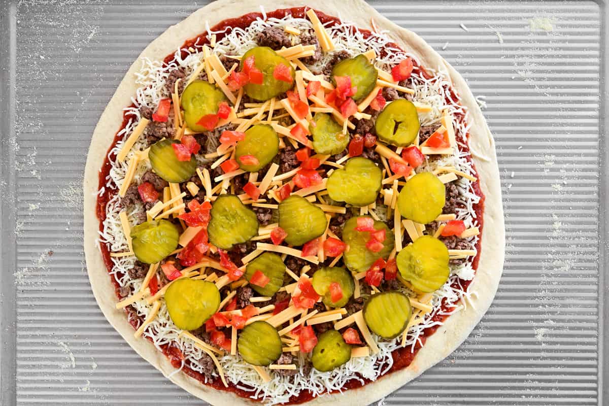 A cheeseburger pizza with tomatoes on top.