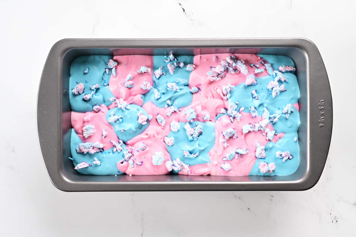 Pink and blue ice cream and cotton candy chunks in a loaf pan.