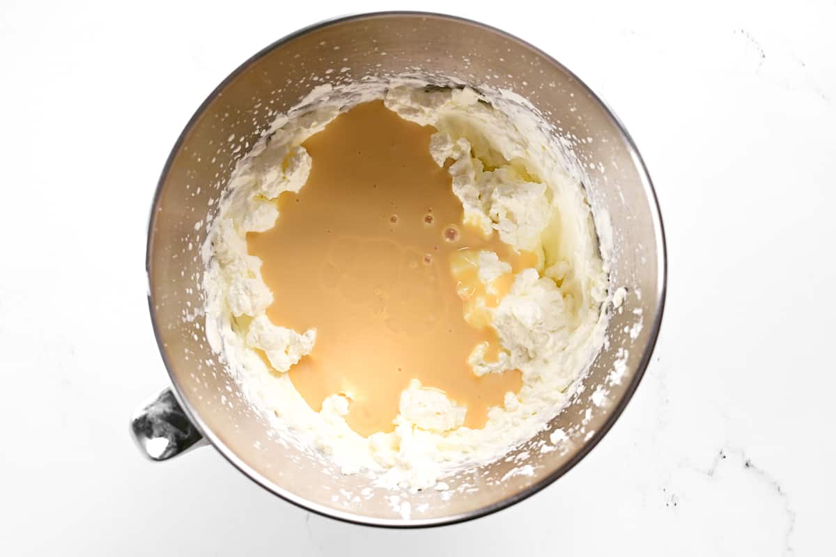 Condensed milk and heavy whipping cream in a metal mixing bowl.
