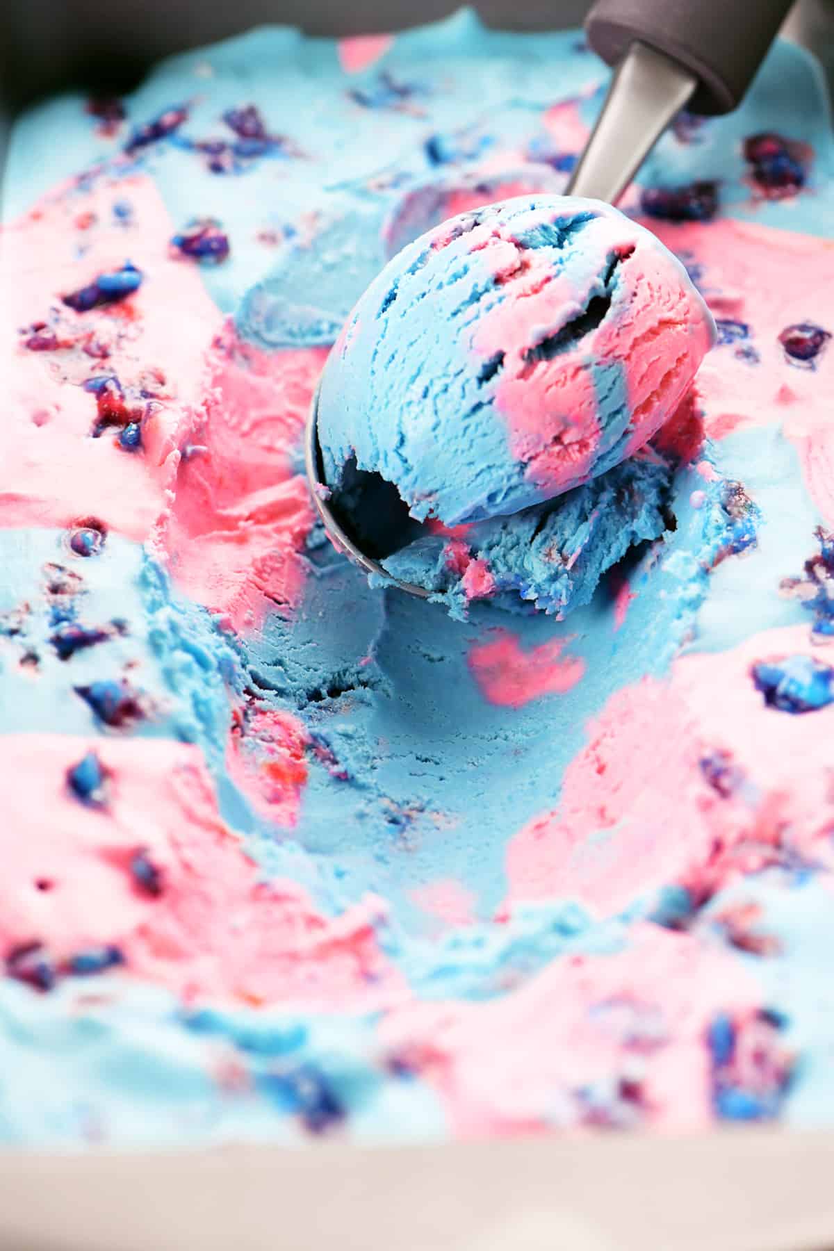 a scoop of pink and blue cotton candy ice cream in a loaf pan.