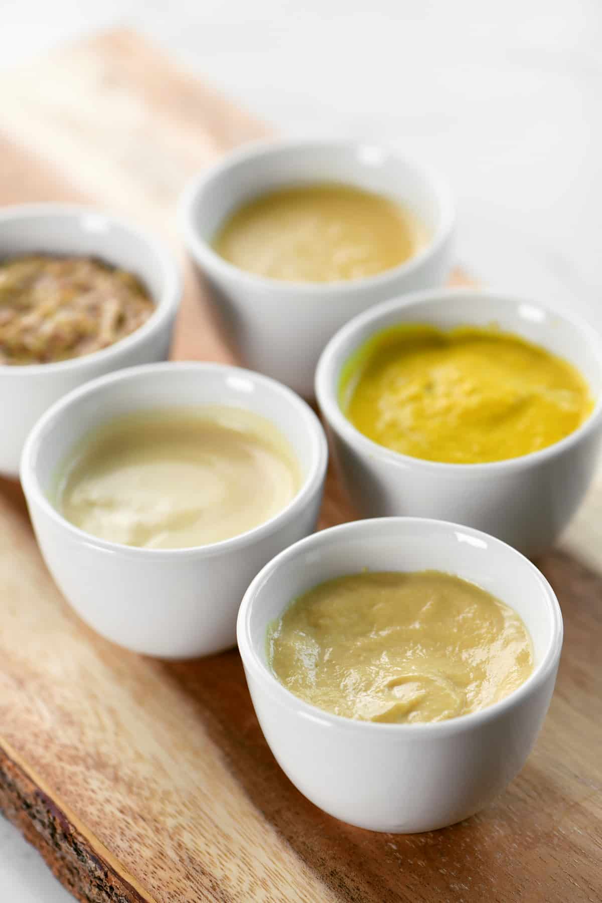 Five Dijon mustard substitutes in small white bowls.