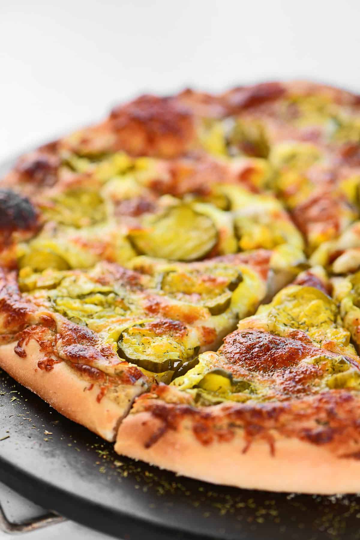 A dill pickle pizza on a baking stone.