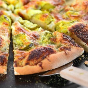 A dill pickle pizza slice on a server.