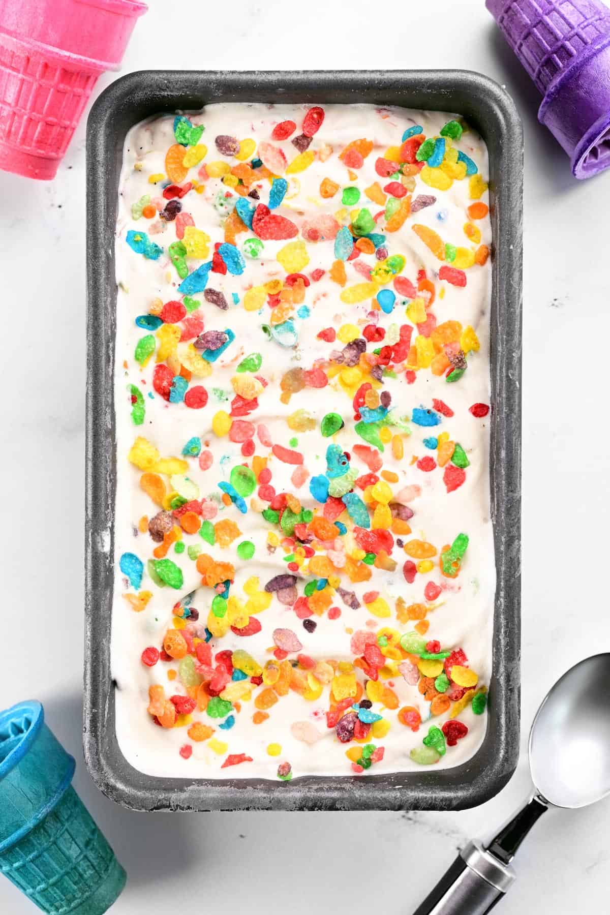 Fruity Pebbles ice cream in a pan with cones.
