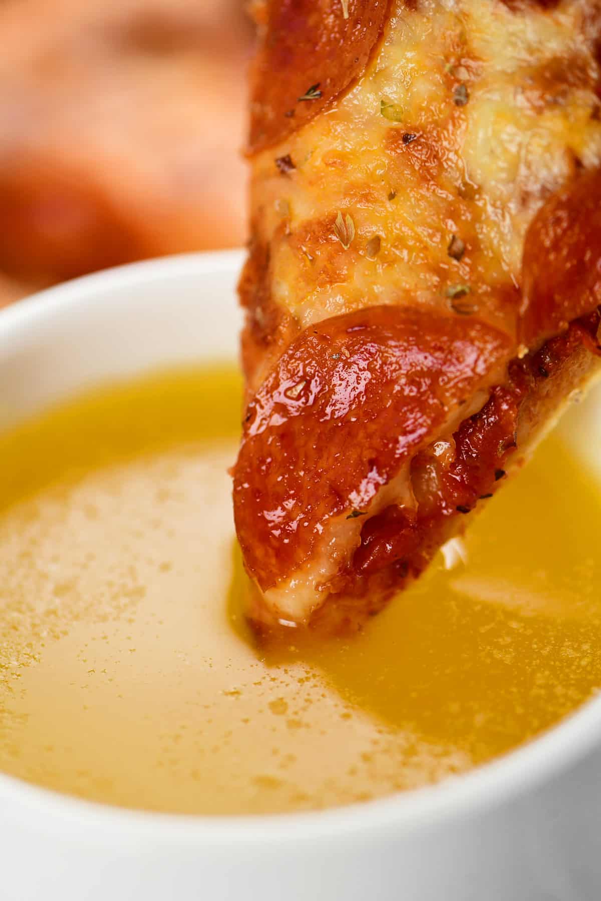 A slice of pizza dipped into garlic butter.