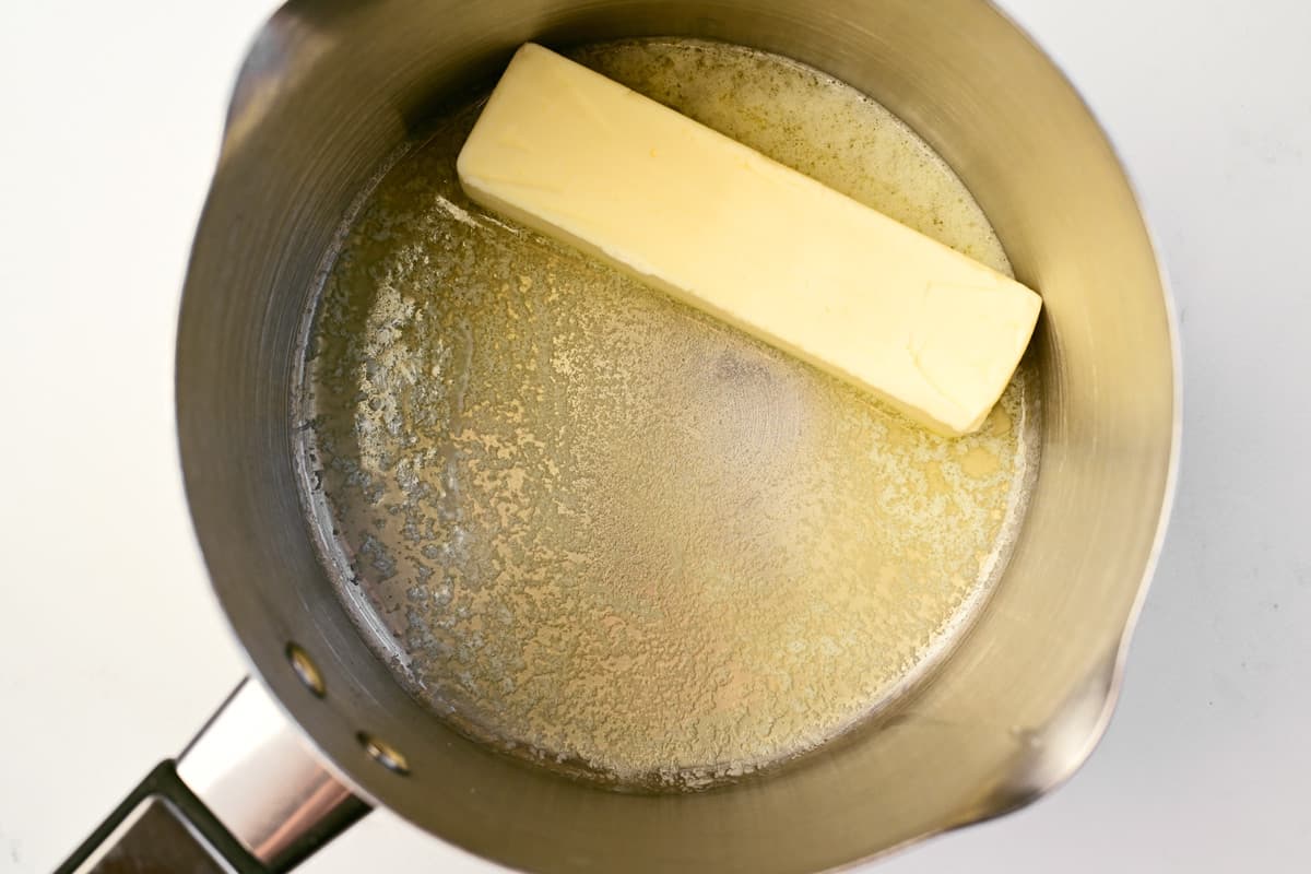 A stick of butter melting in a saucepan.