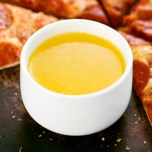 A small white bowl of garlic butter dipping sauce.