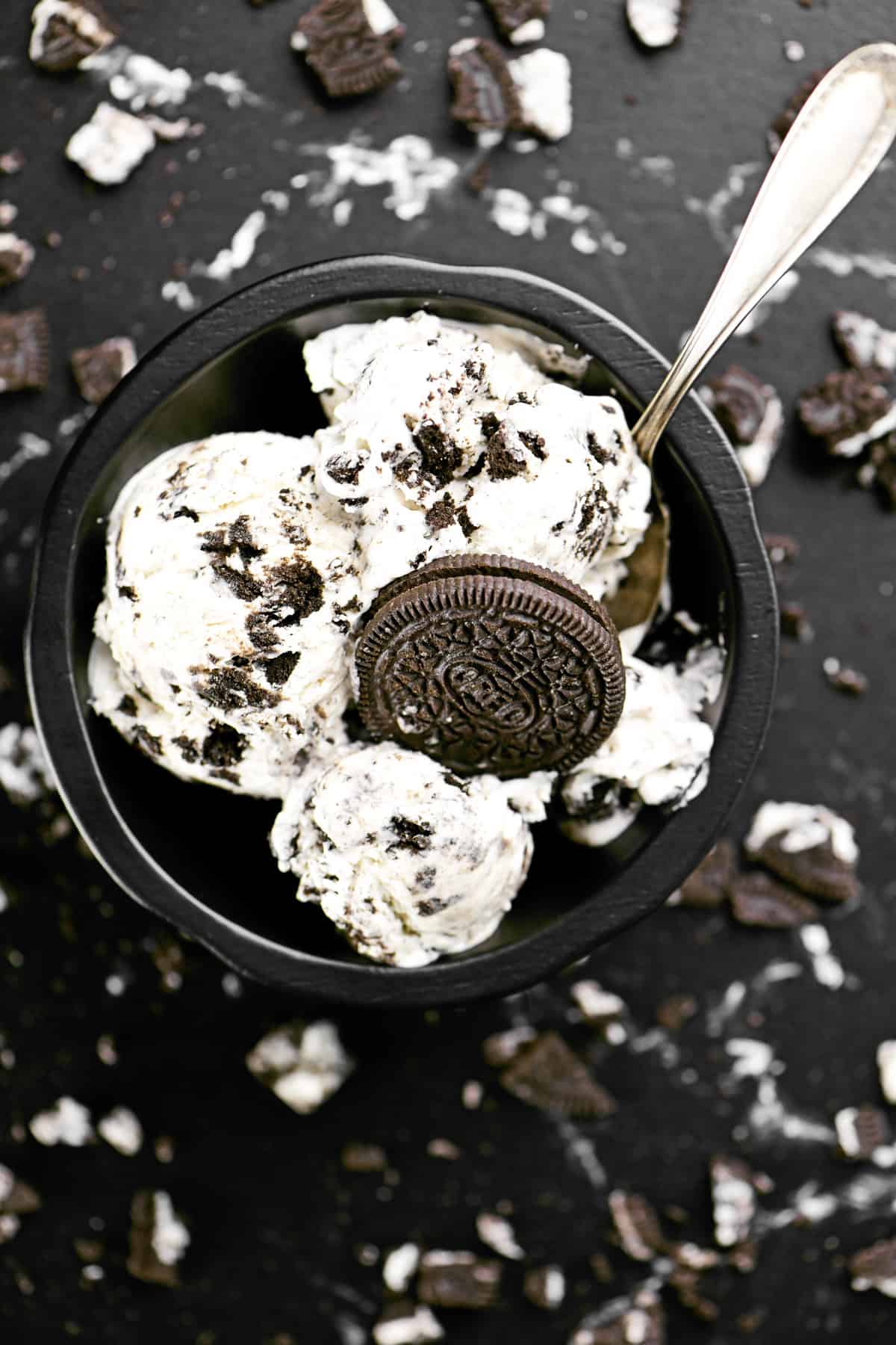 Oreo ice cream in a black bowl with a spoon.