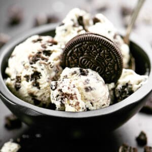 A black bowl with Oreo ice cream and an Oreo cookie inside.