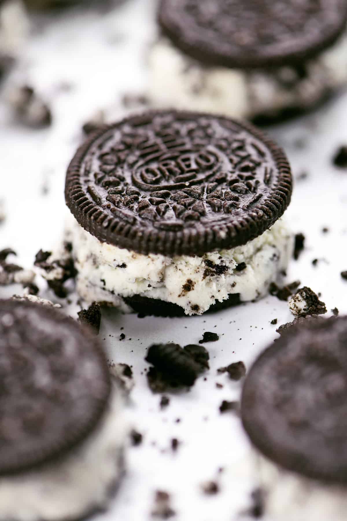 An Oreo ice cream sandwich surrounded by Oreo crumbles.