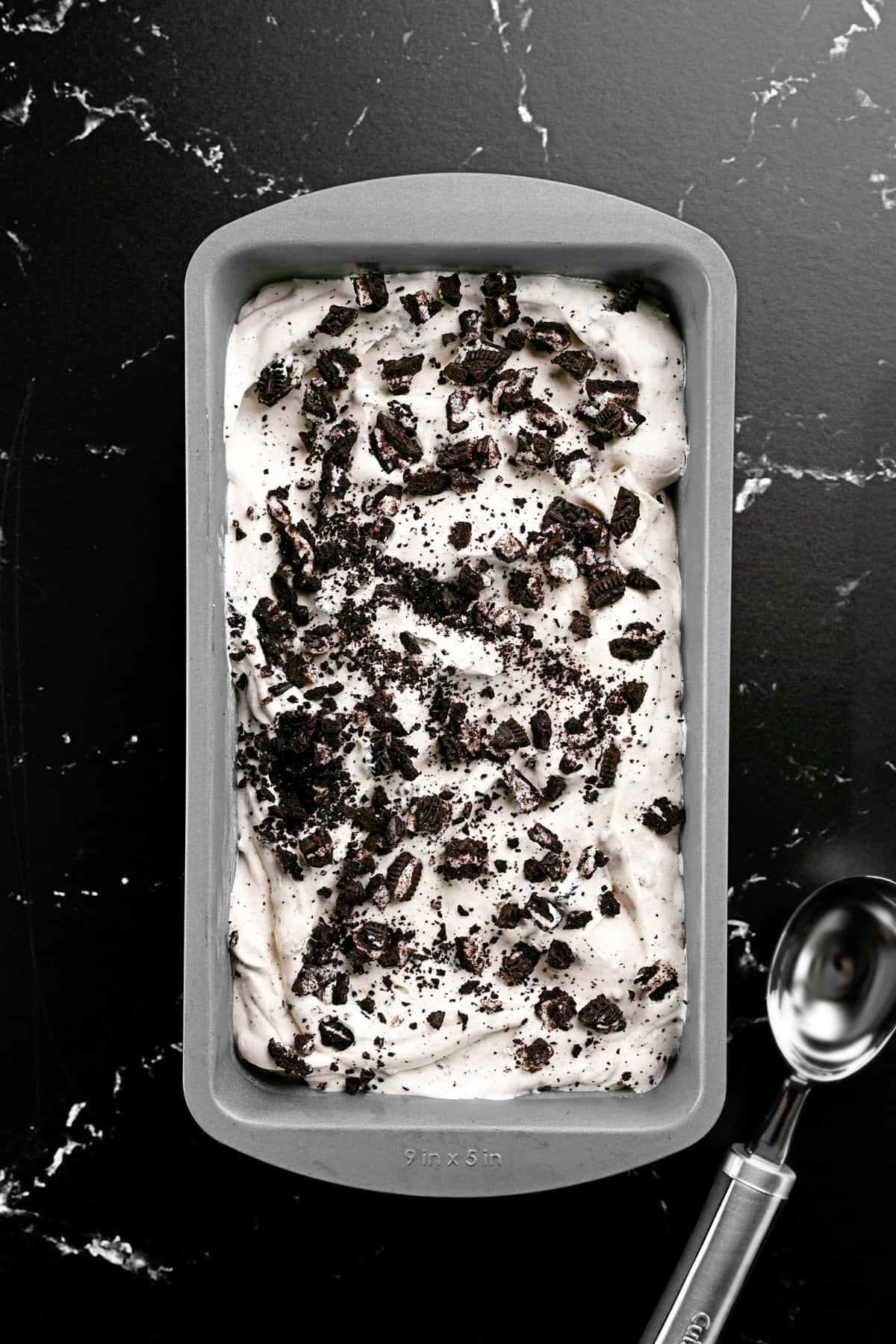 Ice cream in a loaf pan with Oreo cookie crumbles on top.