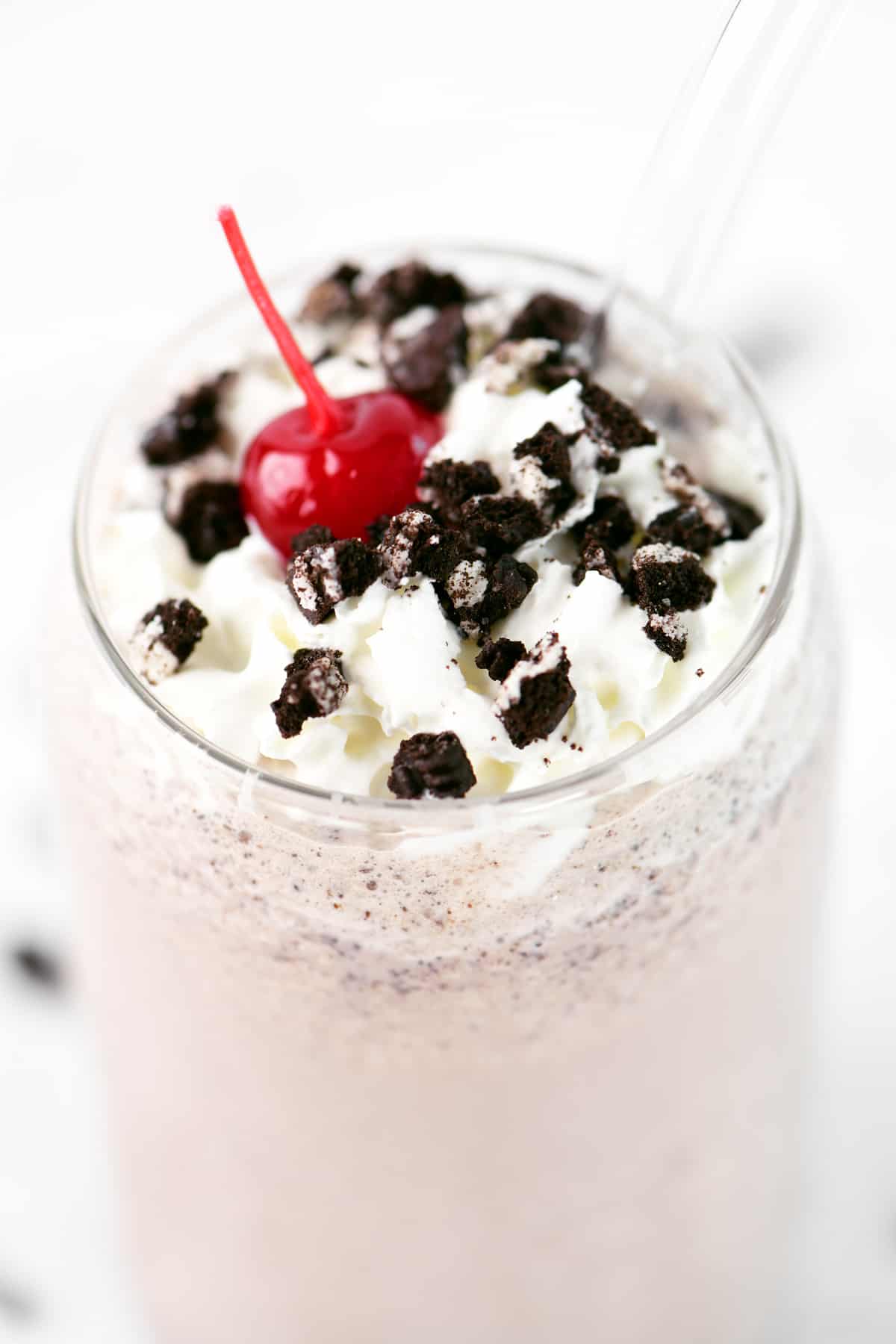 Cookie crumbs ad a cherry with whipped cream on an Oreo milkshake.
