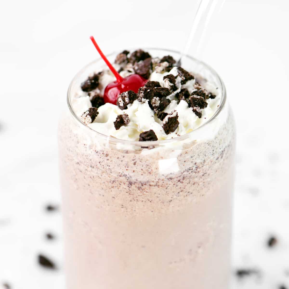 A cherry on top of a cookies and cream milkshake.