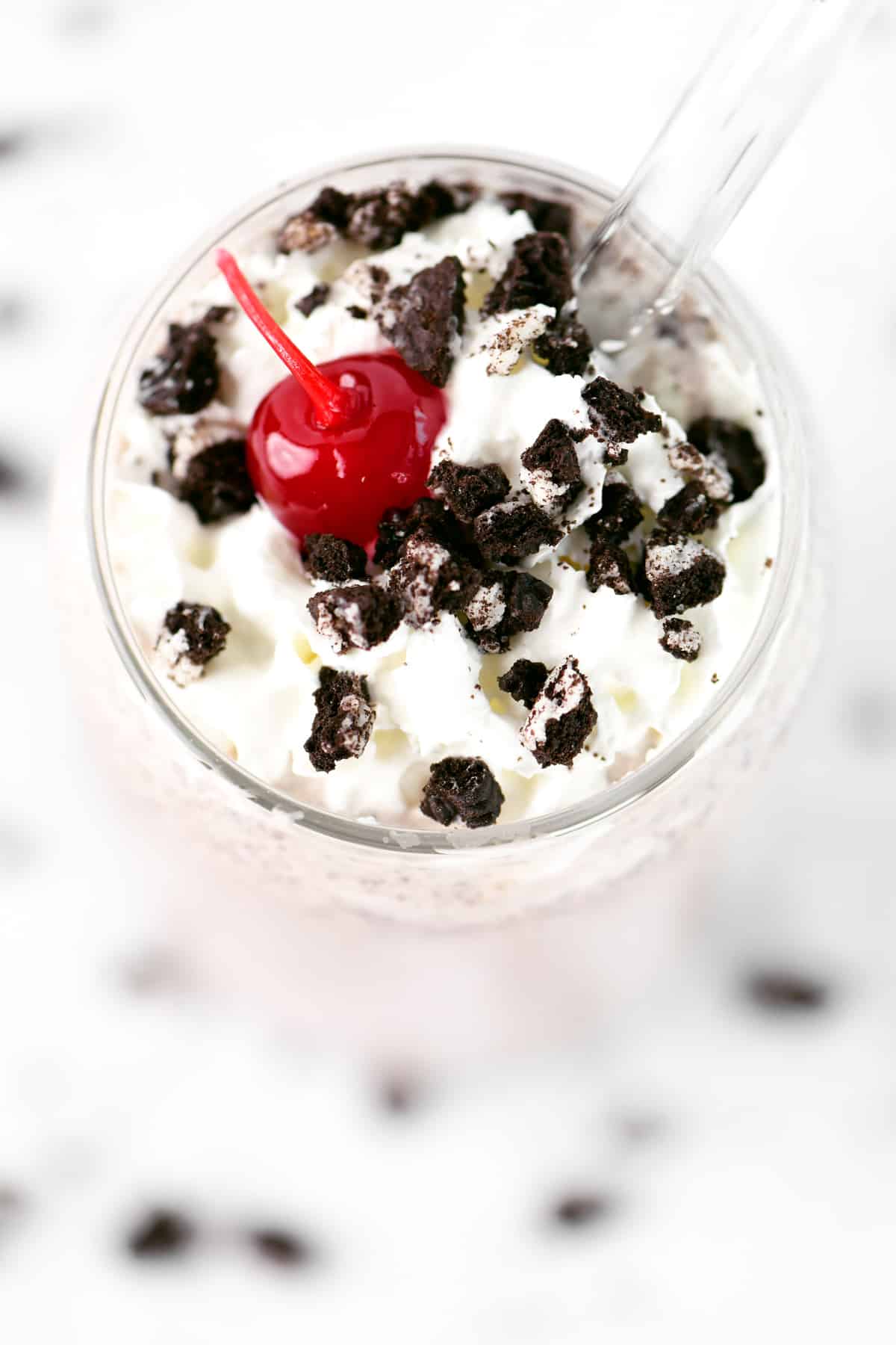 Whipped cream, cookie crumbs and a cherry on a milkshake.