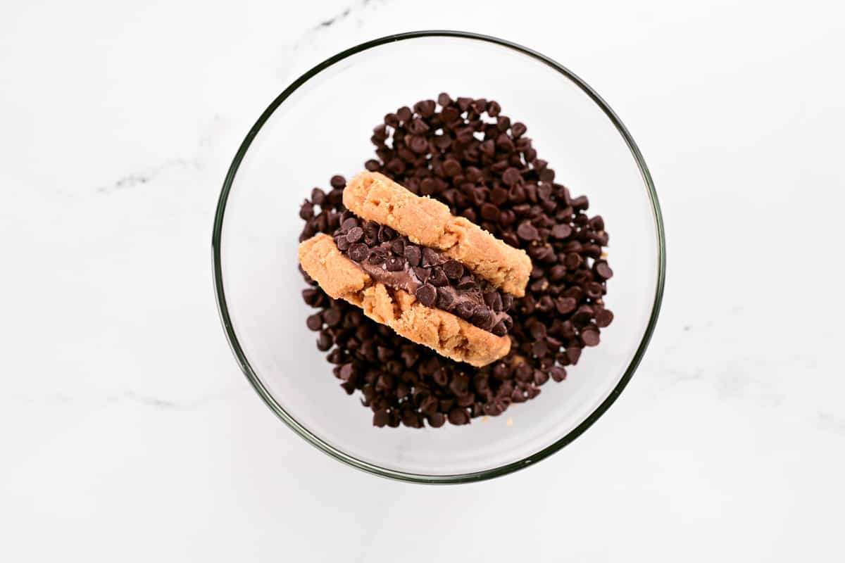 A peanut butter ice cream cookie sandwich in a bowl of chocolate chips.