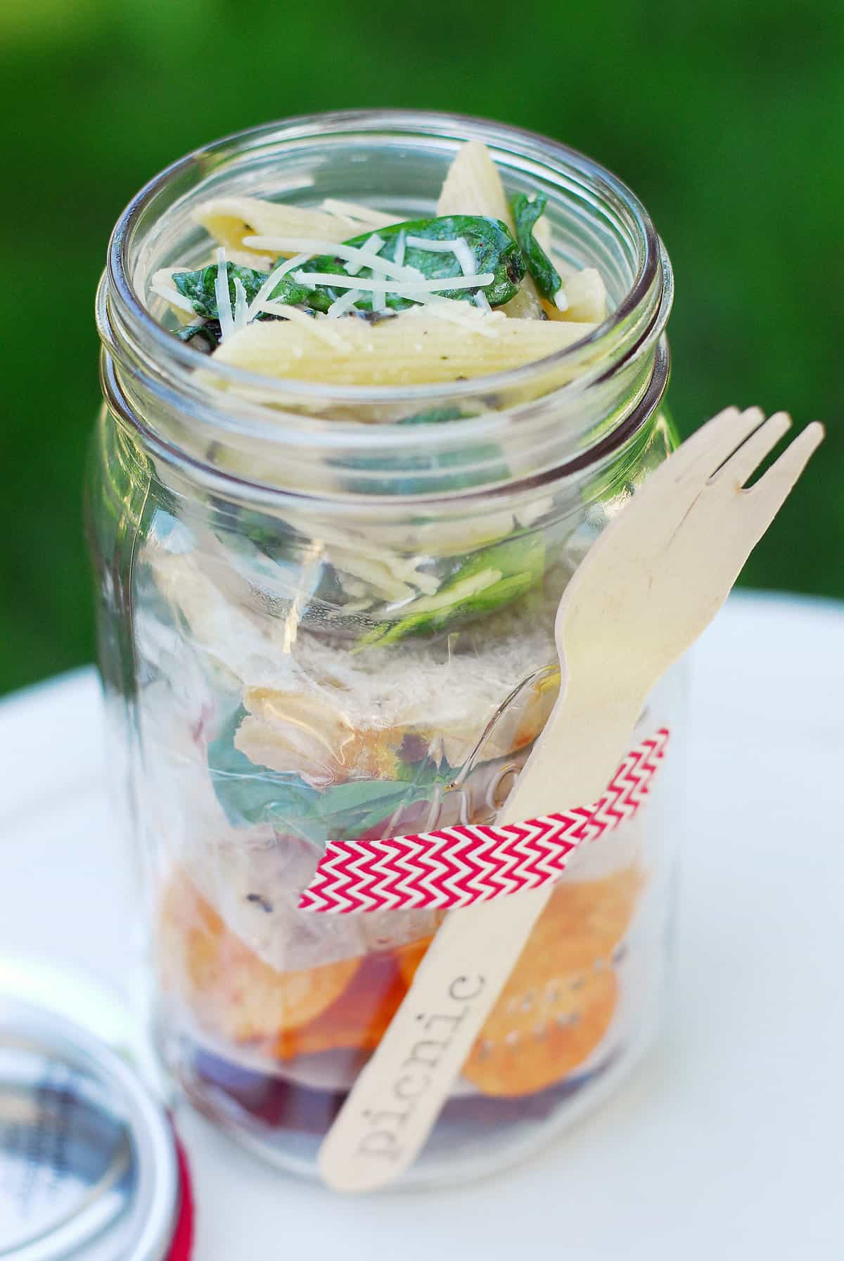 Picnic in a jar topped with salad.